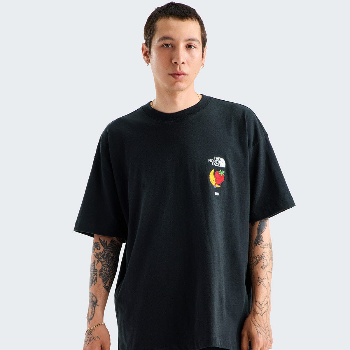 Person wearing a black t-shirt with a colorful logo on a light gray background