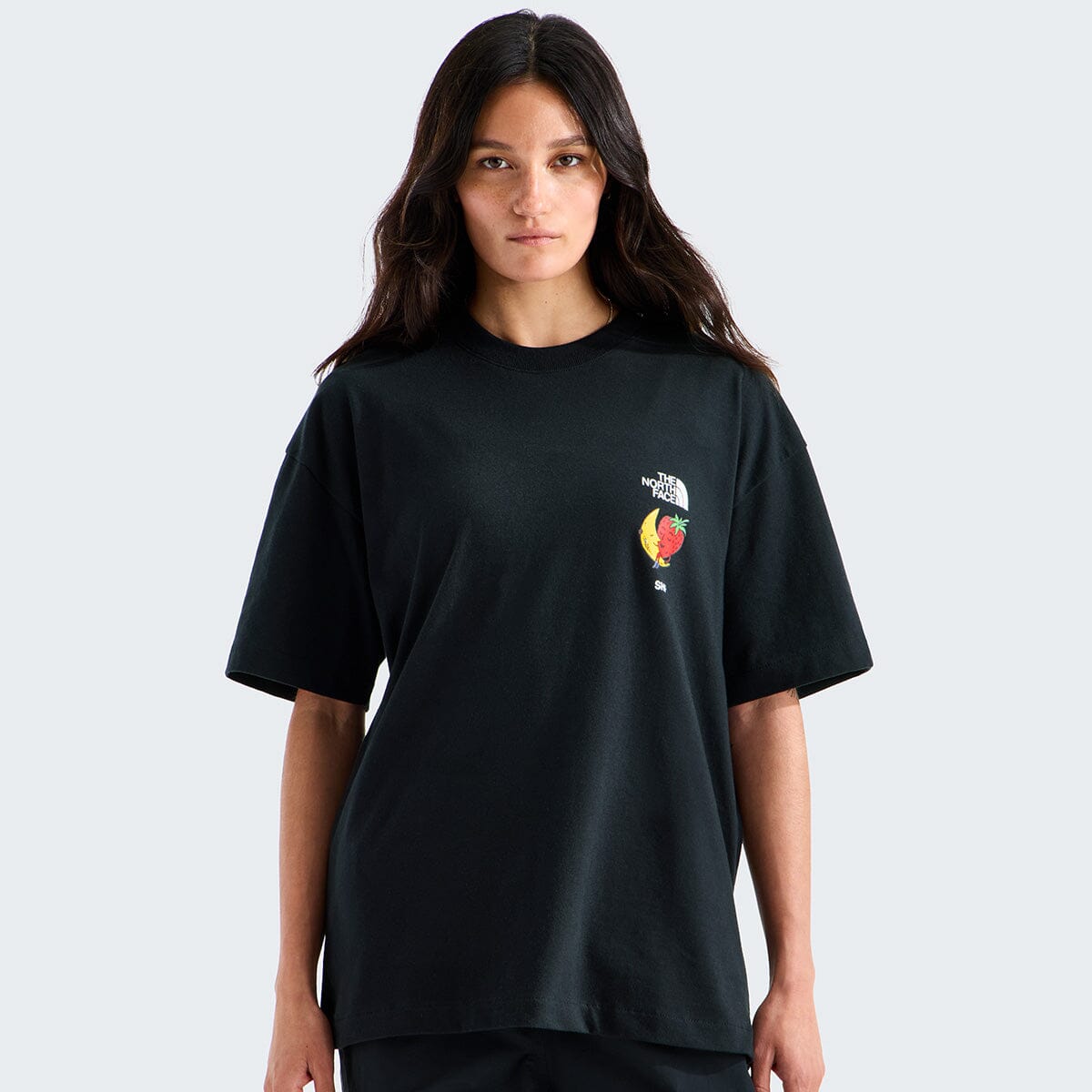 Person wearing a black t-shirt with a logo on a light gray background